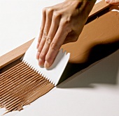 Close-up of hand pulling the comb through dark chocolate, step 2
