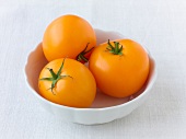 Three yellow tomatoes in bowl