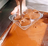 Close-up of chocolate being poured into egg shaped mould, step 1