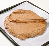 Close-up of sponge cake batter being spread with knife on baking plate