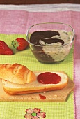 Bowl of chocolate banana cream, strawberries, and strawberry jam on bread