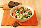 Bowl of colourful rocket salad with tomatoes and figs on orange table mat