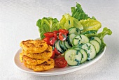 Close-up of potato pancakes with lettuce, cucumber and tomato in dish
