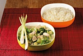 Thai chicken curry with broccoli in yellow bowl and basmati rice in orange bowl