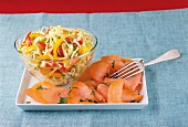 Close-up of salmon in dish and cabbage, peppers and tomatoes in bowl