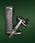 Silver boot, belt, cell phone and ballet flat on green background