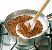 Close-up of cocoa being added in heated fondant, step 2