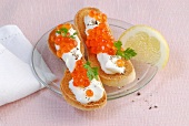 Toasted bread slices topped with creme fraiche and caviar on plate