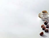 Chocolate pralines and a cup of coffee on white background