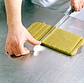 Chef cutting marzipan-pistachio rolled dough, step 5