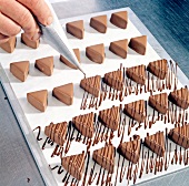 Close-up of pralines being decorated with chocolate coating, step 5