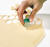 Close-up of marzipan being cut into circular shapes with cutter, step 1