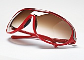 Rote Sonnenbrille mit grauem Streifen, braune Gläser
