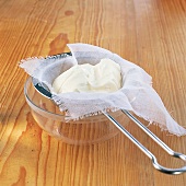 Whey from yogurt separate in bowl by straining cloth on strainer