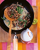 Beef curry with green beans and coconut milk in a wok with wooden spoon