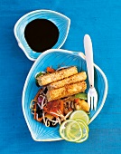 Sesame tofu, stir-fried vegetables, lime slices and bean sprouts in blue bowl