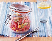 Salad in a preserving jar with glass and fork on table mat