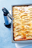 Close-up of kitchen torch being used to caramelize apple pie with cream
