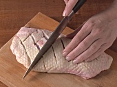 Duck skin being cut with knife for preparation of duck breast, Step 1
