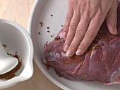 Leg of venison being rubbed with spices, step 2