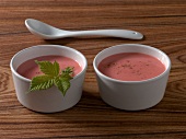 Two bowls with raspberry mustard sauce and mint on wooden board