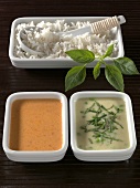 Green curry and peanut curry sauces with rice on wooden board