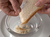 Slice of bread being broken into small pieces for preparation of orange aioli, step 2