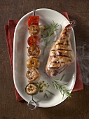 Grilled turkey with rabbit, mushrooms and peppers in skewer on plate