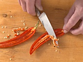 Halved chilli being deseeded with knife for preparation of physalis salsa, step 3