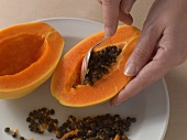 Scooping core of papaya with spoon for preparation of pork, step 1