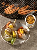 Two salmon steaks on grill and two mango and prawn skewers on plate