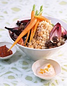 Couscous with carrots and chickpeas in bowl besides sour cream