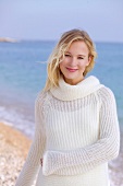 Blonde Frau in weißem Pullover am  Meer