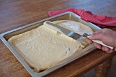 Dough being spread on baking sheet for preparation of biscuit rolls, step 1