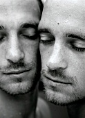Close-up of two men touching cheek to cheek with their eyes closed
