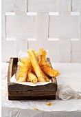 Cheese coated salsify on wooden tray