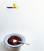 Cold elderberry soup with apples and creme fraiche on plate on white background