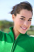 Portrait of beautiful brunette woman with hair back plugged wearing green sweater, smiling