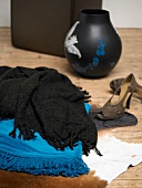 Black and turquoise blankets with shoes and vase by side