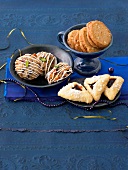 Almond cookies with pistachios and spiced biscuits in bowl and triangular cookies on plate