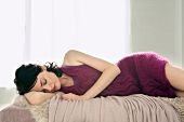 Beautiful young woman wearing purple woollen dress sleeping on bed