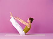 Pilates - Teaser: Frau sitzt, Beine heben, Arme nach vorn, Step 2a