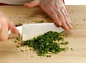 Chopping herbs with knife on cutting board, step 4