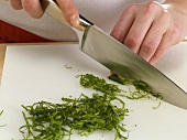 Basil leaves being cut into strips with knife, step 2