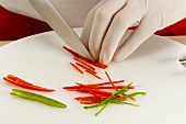 Chilli pepper being cut into strips with knife, step 3