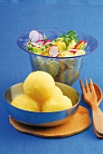 Potato salad with radish and potato dumplings in serving dish