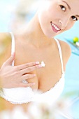 Portrait of pretty woman wearing bra applying cream on her cleavage