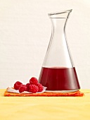 Raspberry syrup in carafe with raspberries