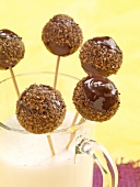 Close-up of chocolate balls on wooden skewers in glass