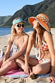 Zwei Frauen sitzen am Strand und haben Spaß